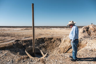 Bill Wight looks at the well that leaked enormous volumes of saltwater on his property. It took crews over a month to seal the well and stop the leak. Credit: Sarah M. Vasquez/The Texas Tribune