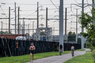 People pass electrical power lines on a a bike path in Arlington, Va. Credit: Andrew Caballero-Reynolds/AFP via Getty Images