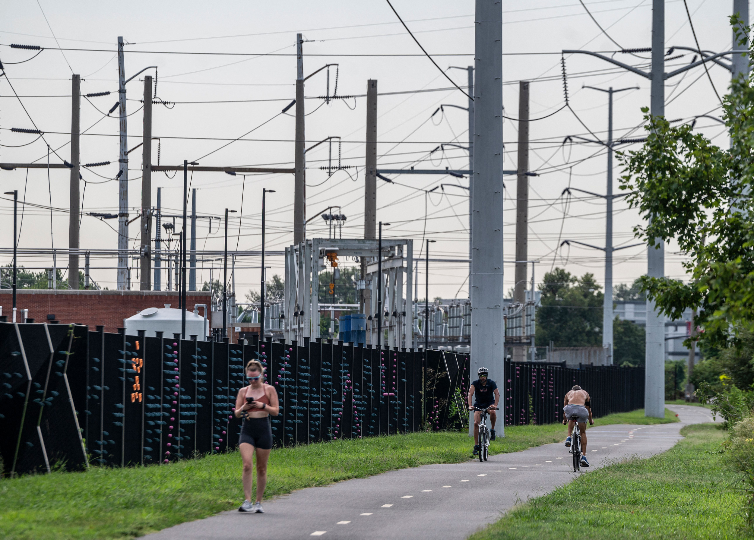 People pass electrical power lines on a a bike path in Arlington, Va. Credit: Andrew Caballero-Reynolds/AFP via Getty Images