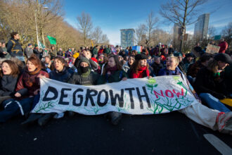 Demonstrators hold a sign reading Degrowth Now after they blocked the A12 highway during an Extinction Rebellion protest on March 11, 2023 in The Hague, Netherlands. Credit: Michel Porro/Getty Images