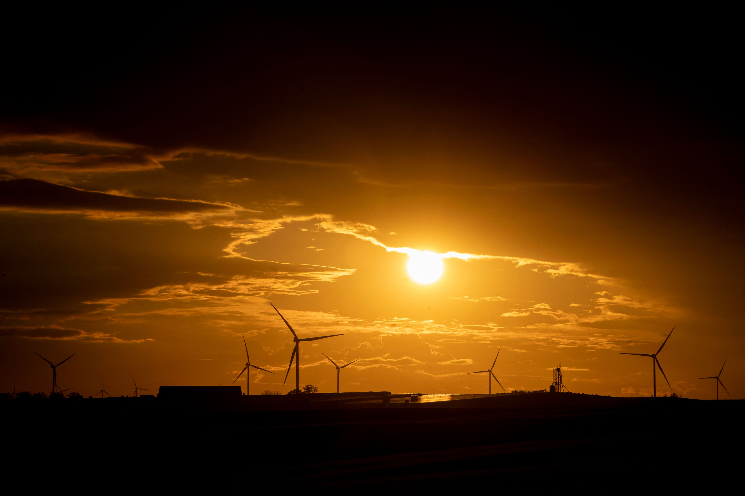 Wind turbines are seen at sunset in Williamsburg, Iowa on Aug. 14, 2023. Slow wind speeds in the Midwest during warmer months contributed to the decrease in electricity generated from wind farms. Credit: Stefani Reynolds/AFP via Getty Images