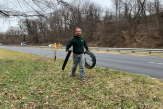 Nathan Harrington, who leads Ward 8 Woods Conservancy, carries a broken tire visible from the road to his truck. Credit: Kayla Benjamin/The Washington Informer
