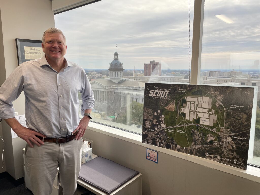 With the South Carolina statehouse behind him, Jeff Ruble, director of the Richland County Economic Development Office, shows the site plan for Scout Motors new $2 billion plant. Credit: Marianne Lavelle/Inside Climate News